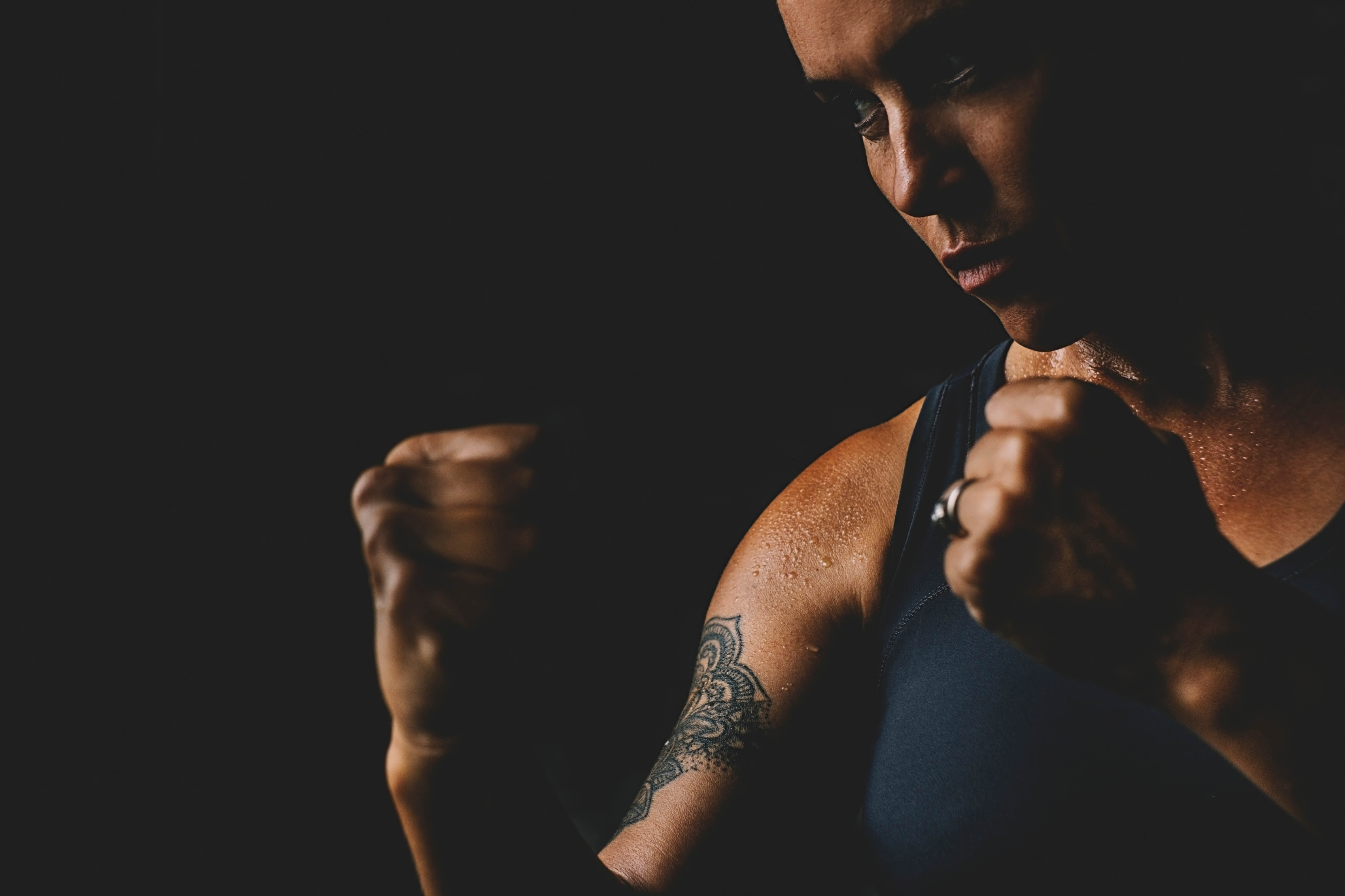 Strong woman boxer with a tattoo, with her fists up in a dark room Strong woman boxer with a tattoo, with her fists up in a dark room